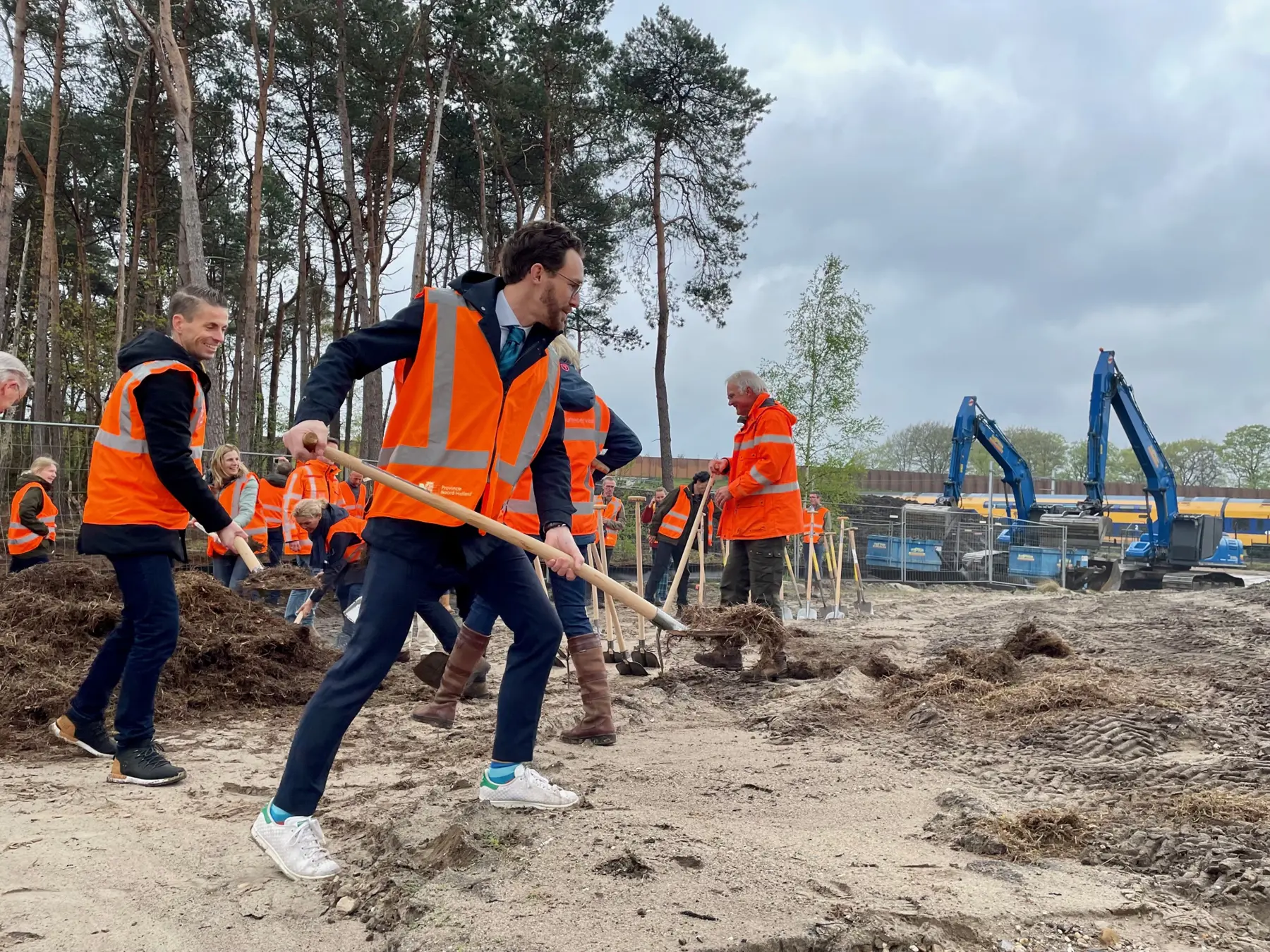 ProRail regiodirecteur Harro Homan (l) en wethouder Arno Scheepers (midden) scheppen het laatste schepje heidemaaisel op de brug