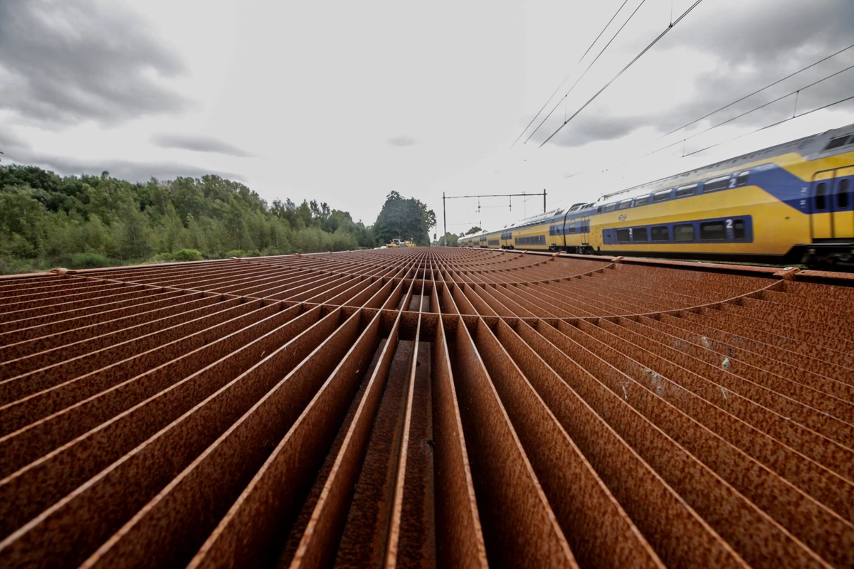 Een NS trein passeert het nieuwe geluidsscherm in Susteren