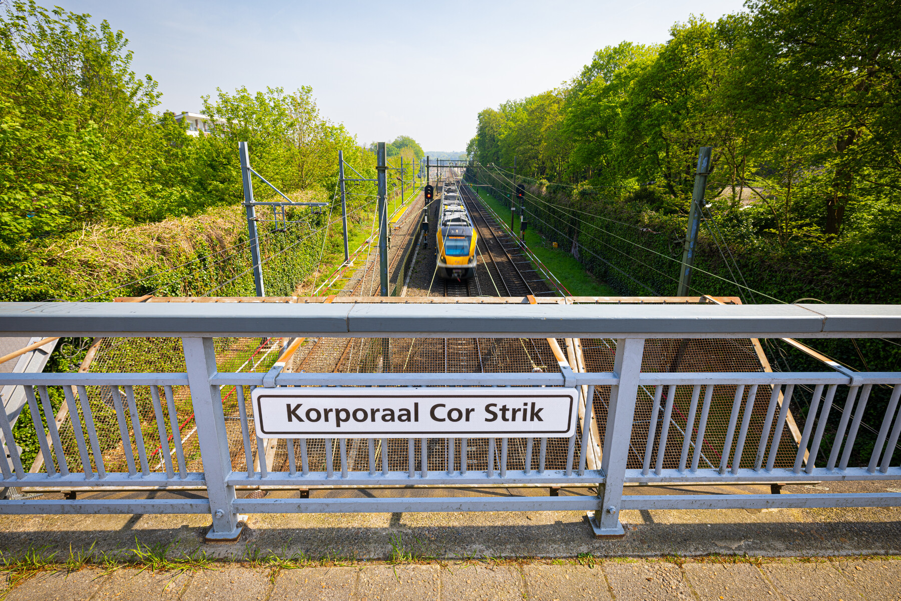 Het bordje in het midden van de brug tegen het hekwerk naast het fietspad