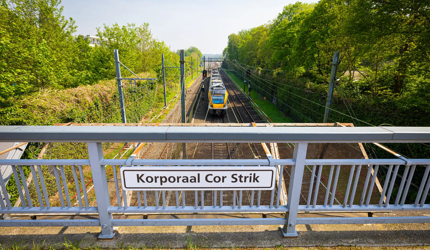 Het bordje in het midden van de brug tegen het hekwerk naast het fietspad