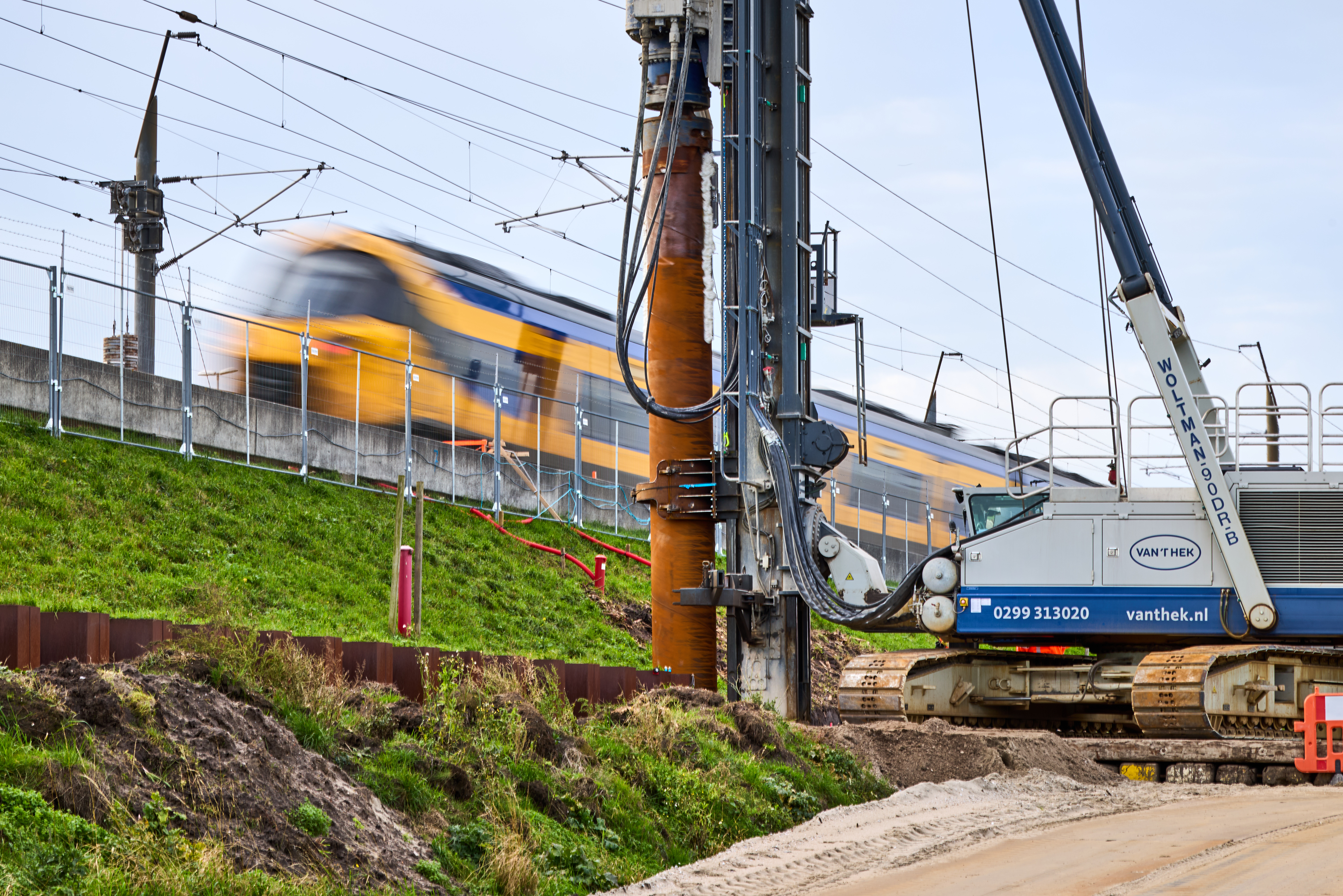 De eerste paal wordt de grond ingedraaid, terwijl de treinen gewoon doorrijden