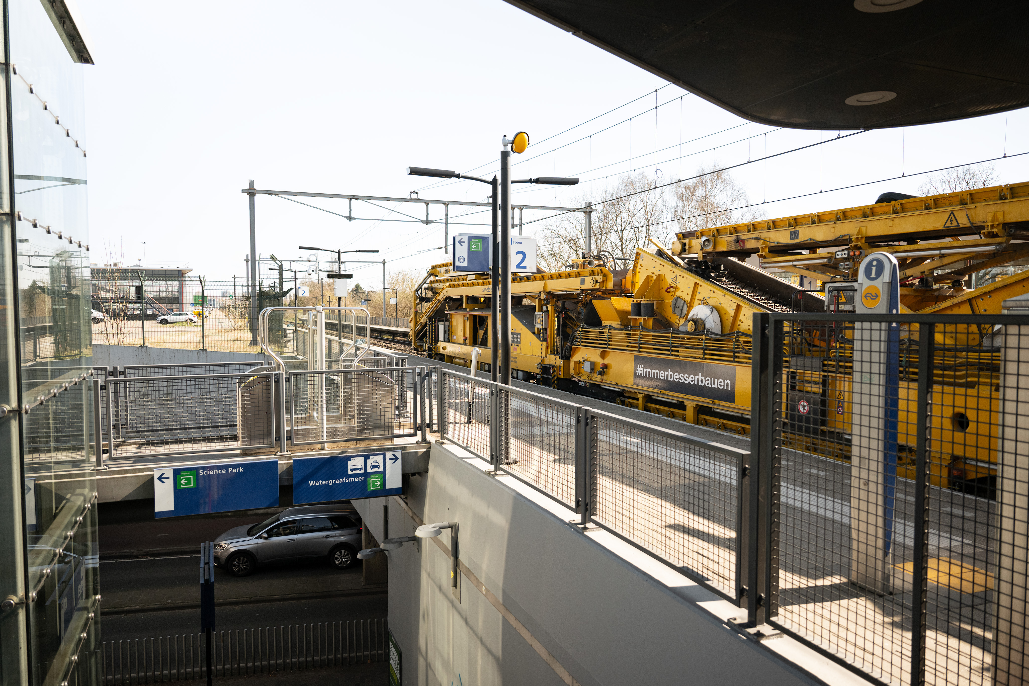 De rijdende fabriek passeert stapvoets een verlaten station Amsterdam Science Park