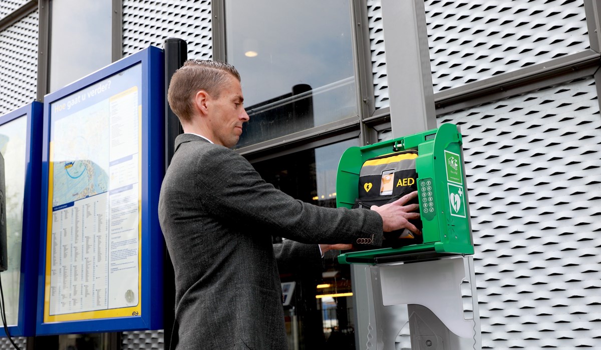 Regiodirecteur Harro Homan plaatst een nieuw AED op een station