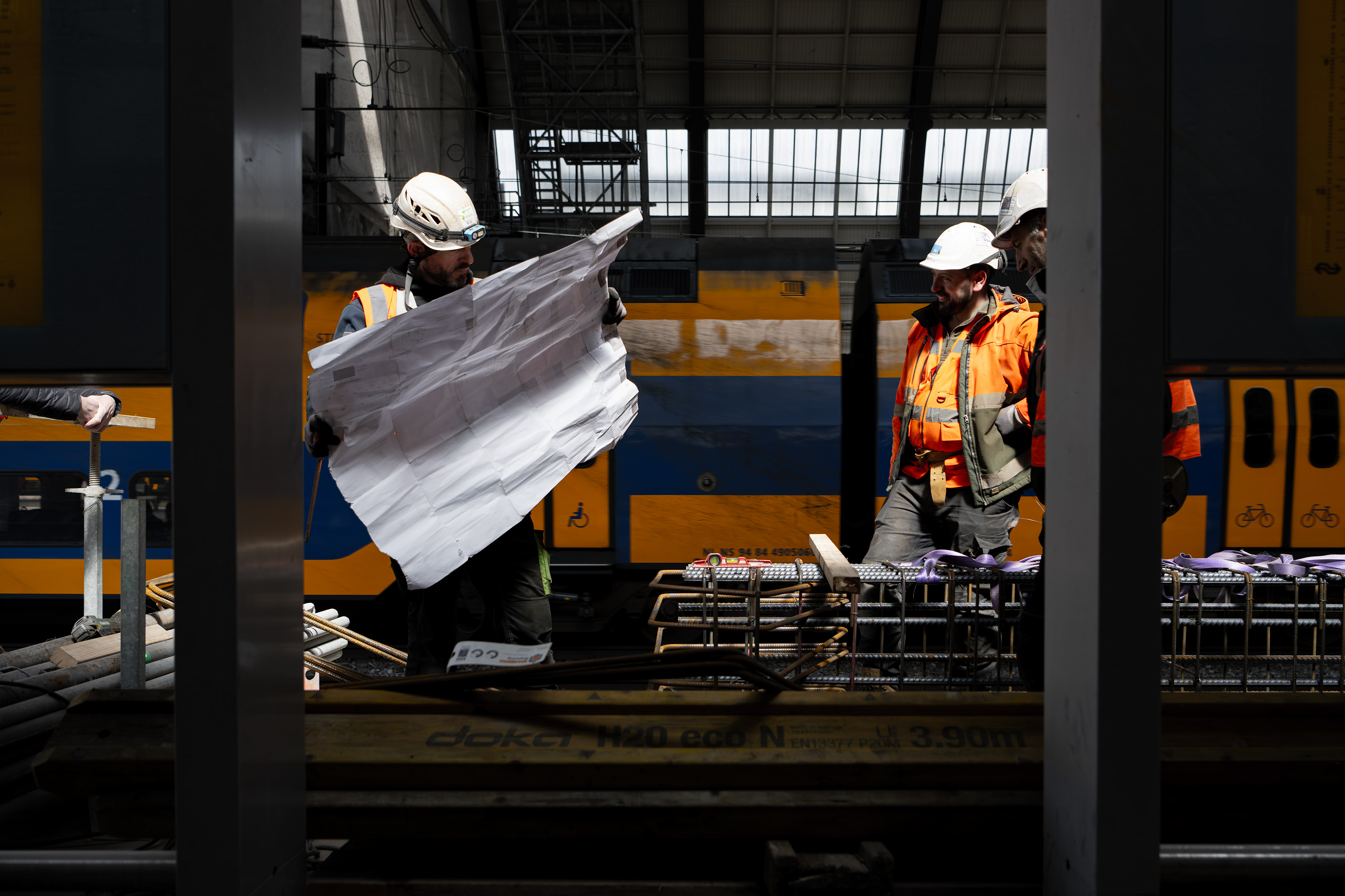 Betonvlechten is een precieze klus. Met de tekening bij de hand moet dat helemaal goed komen. Deze mannen zijn de wapening voor in de betonnen balk bij het perron aan het vlechten 