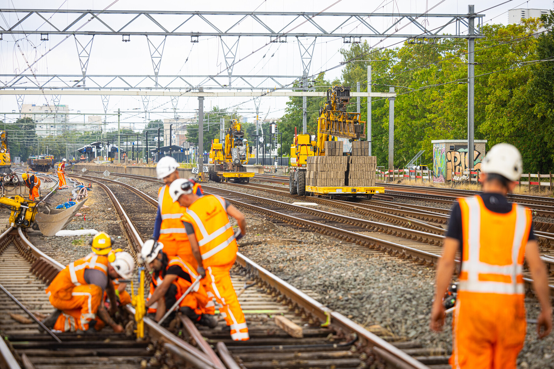 Werk aan het wissel met op de achtergrond de nieuwe tegels voor op de perrons