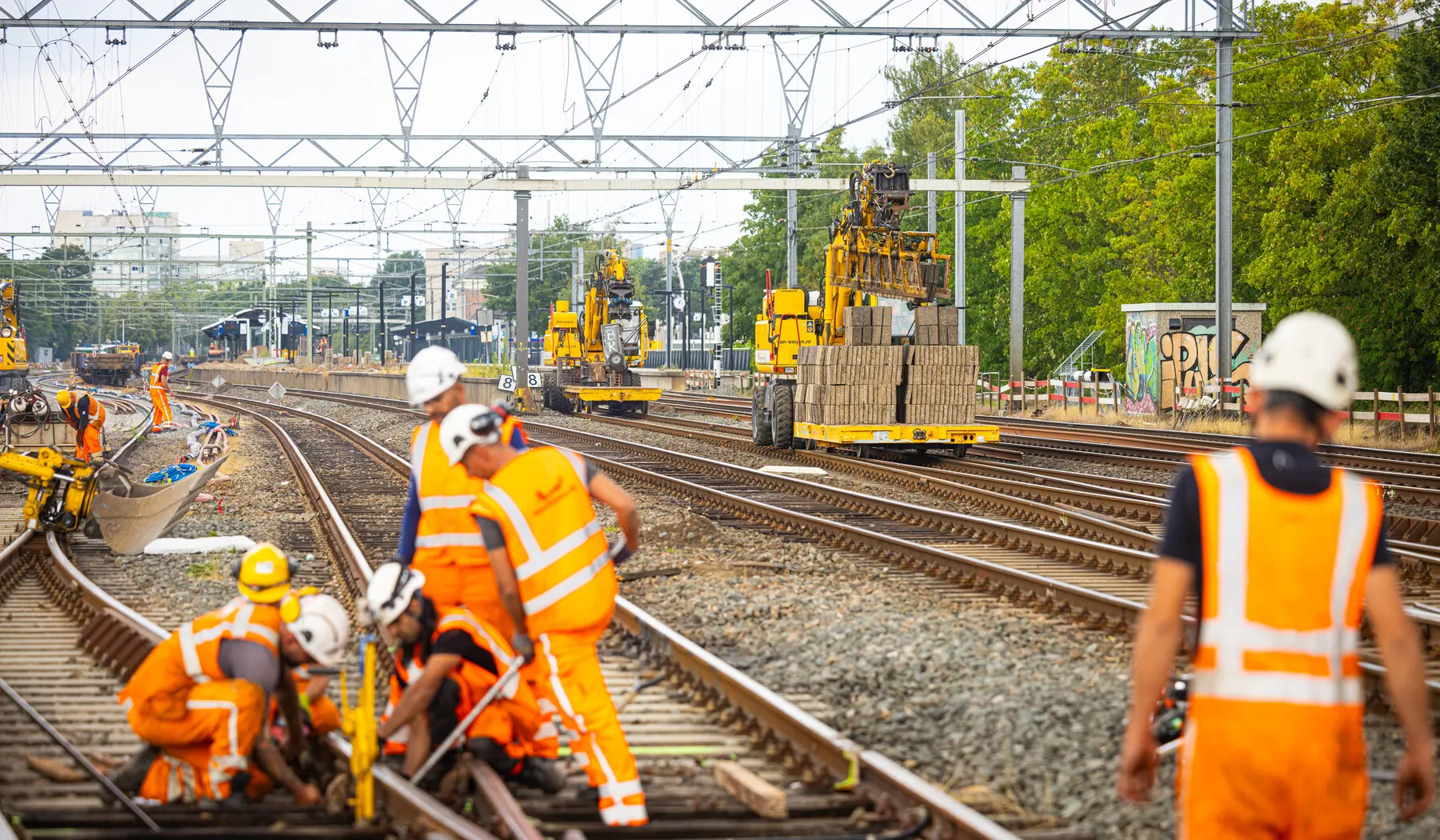 Werk aan het wissel met op de achtergrond de nieuwe tegels voor op de perrons
