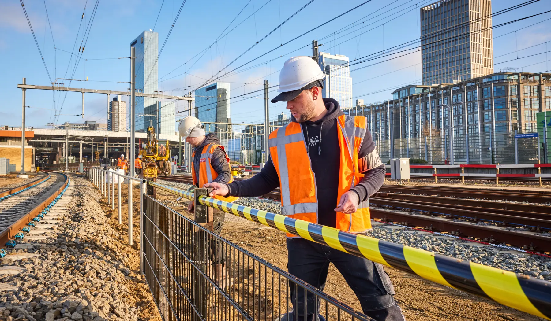 Deze mannen plaatsen een hekwerk: de scheiding tussen machinistenpad en sporen. Hierdoor kunnen machinisten veilig naar de treinen lopen