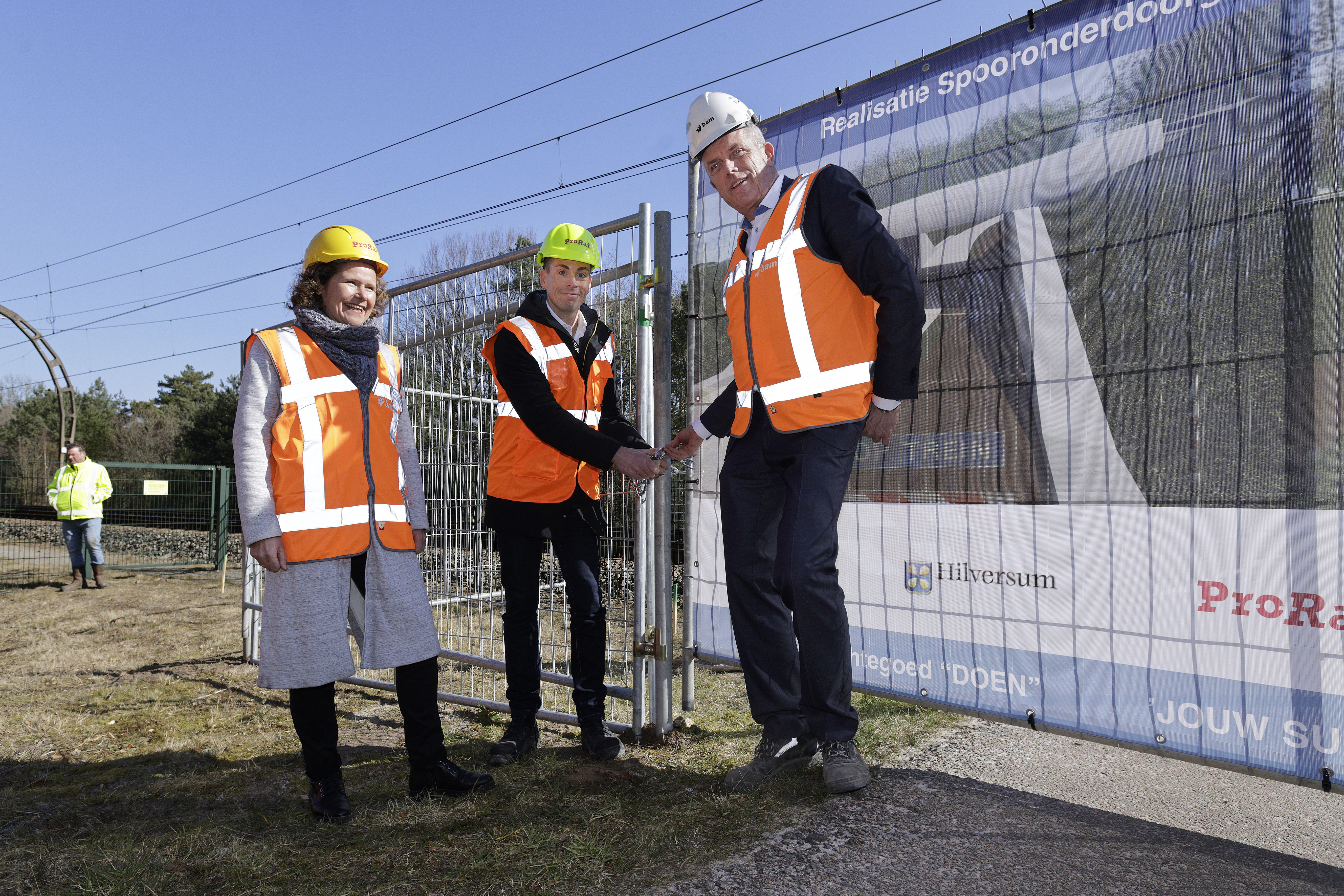 Harro Homan, regiodirecteur bij ProRail, sluit samen met Annette Wolthers, wethouder van gemeente Hilversum, en Alfred Siemes, directeur Verwerving Civiel bij BAM Infra Nederland, de overweg af