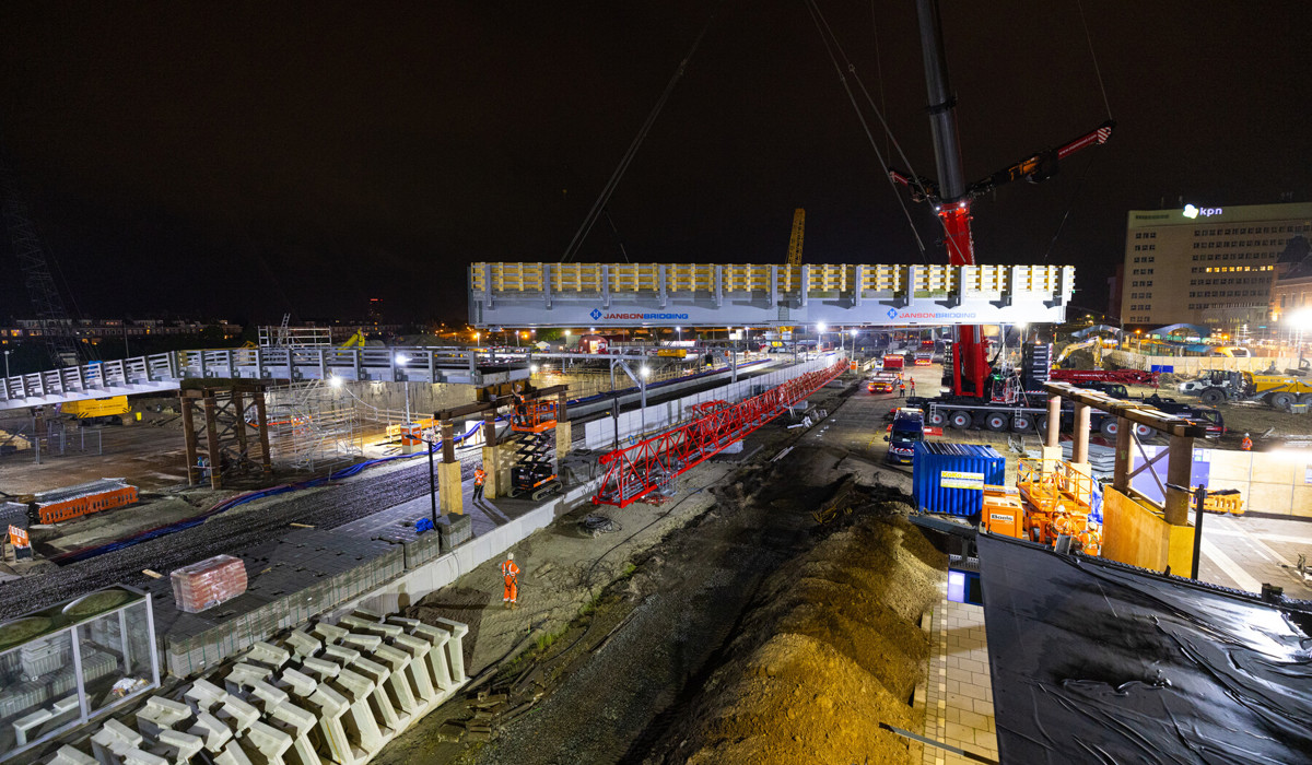 Het hijsen van de brugdekken voor de hulpbrug over het spoor
