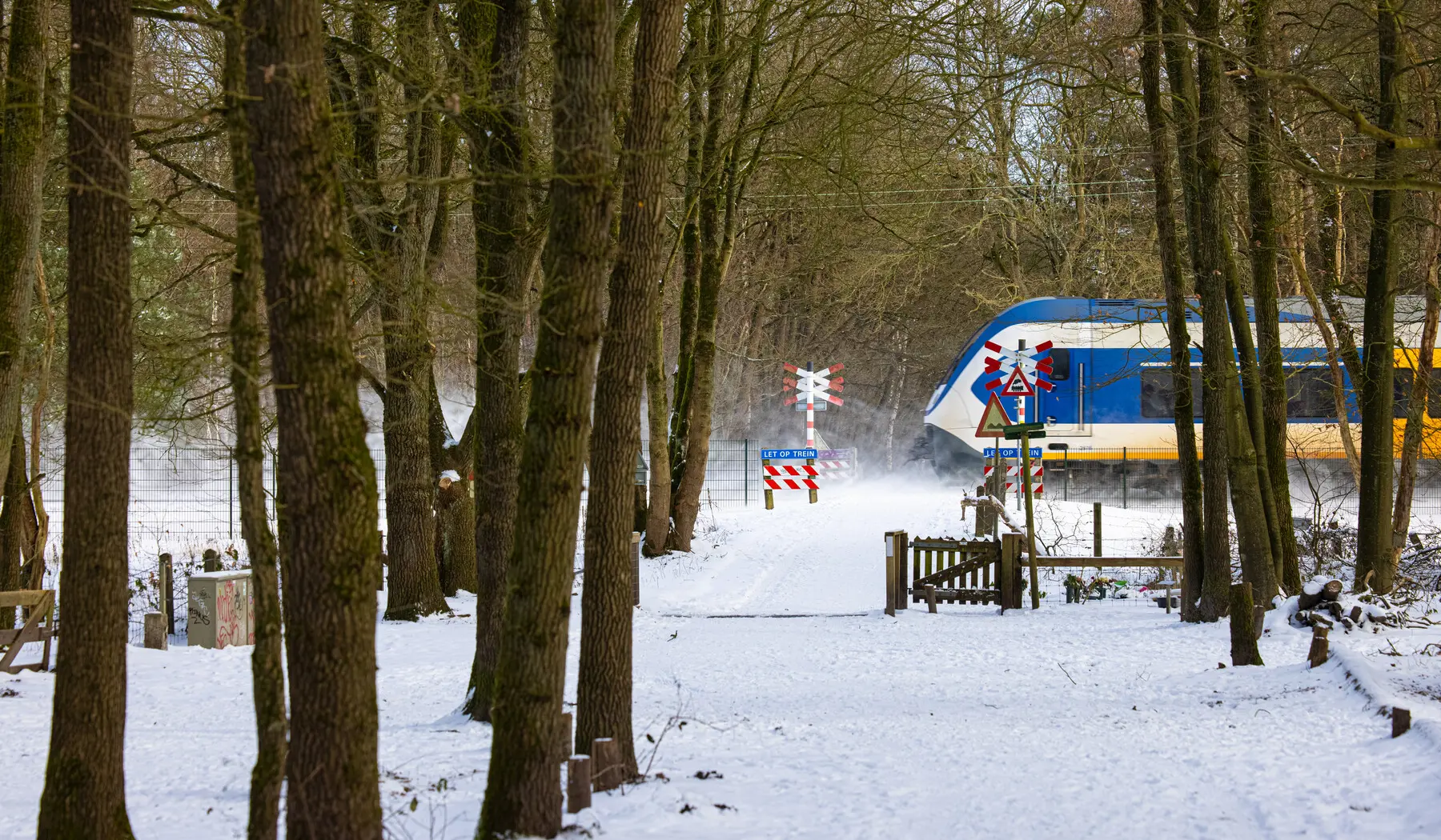 Sprinter in de sneeuw bij een overweg