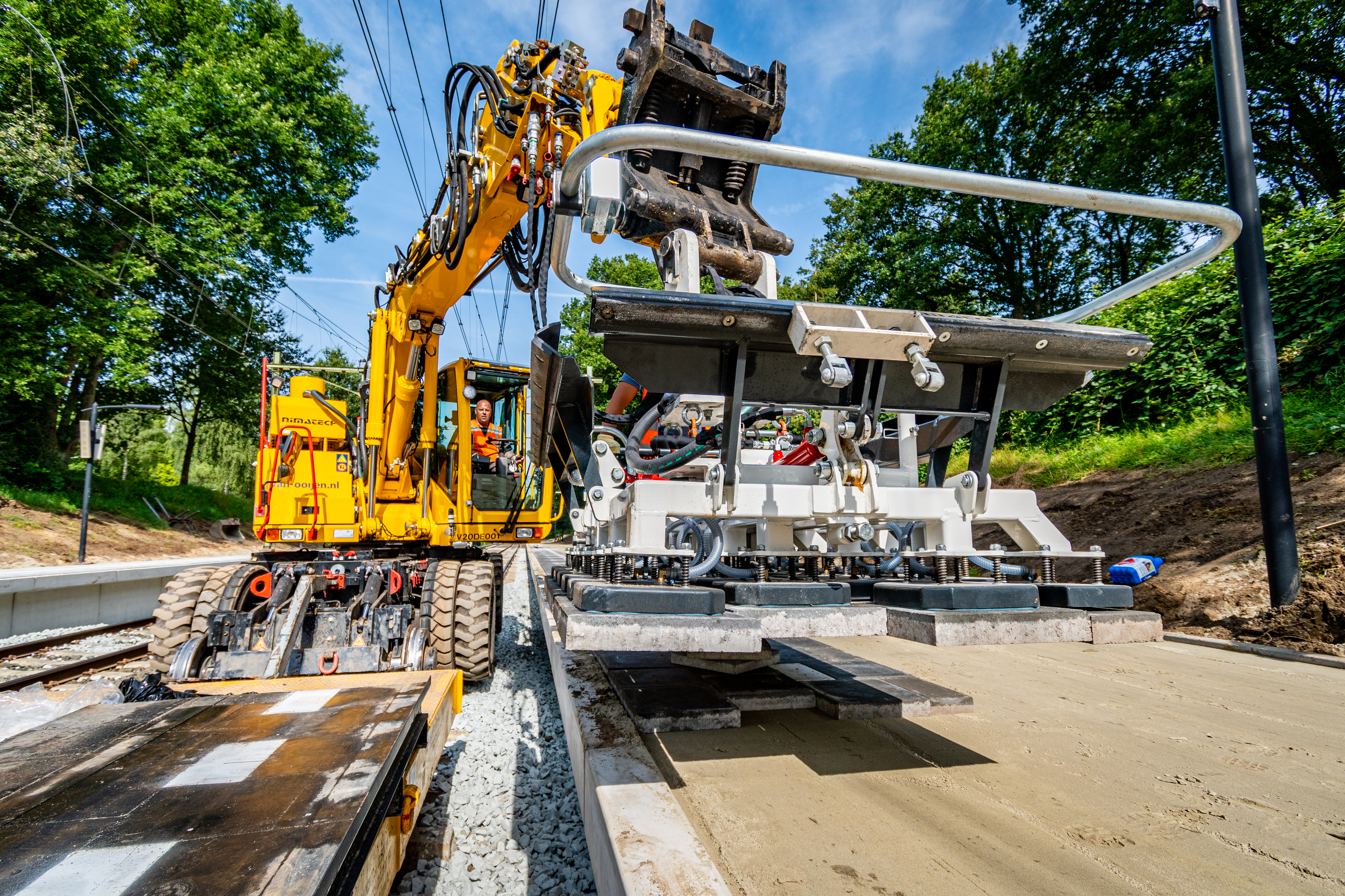 De aangepaste spoorkraan hevelt de tegels  tot boven het perron