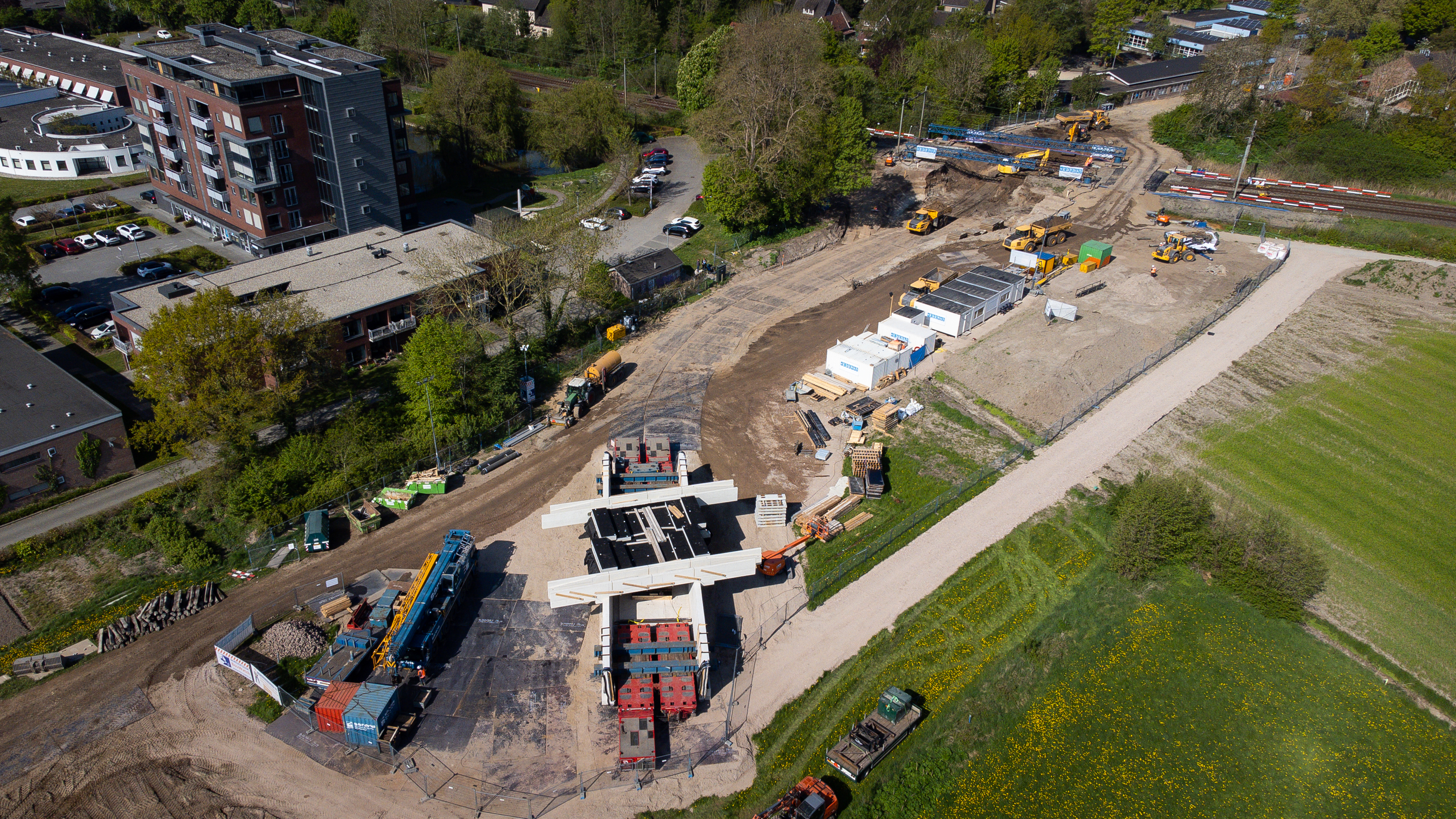 De tunnel is intussen voorgebouwd op het werkterrein naast het spoor. Op de foto zie je hem (midden onderaan) klaarliggen. 