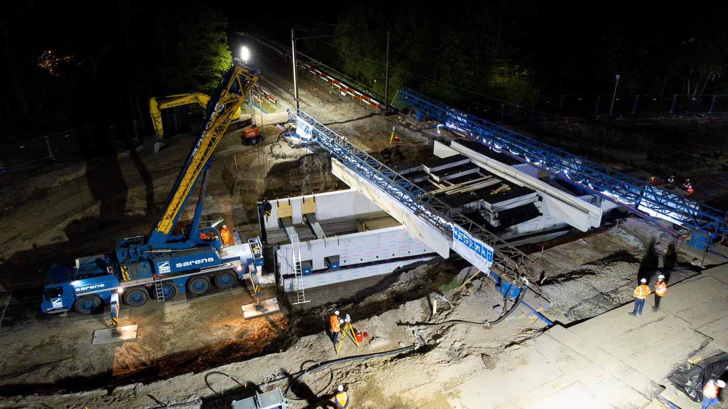 Een kabelbrug (blauw van kleur) houdt tijdelijk de kabels vast die langs het spoor lopen. 