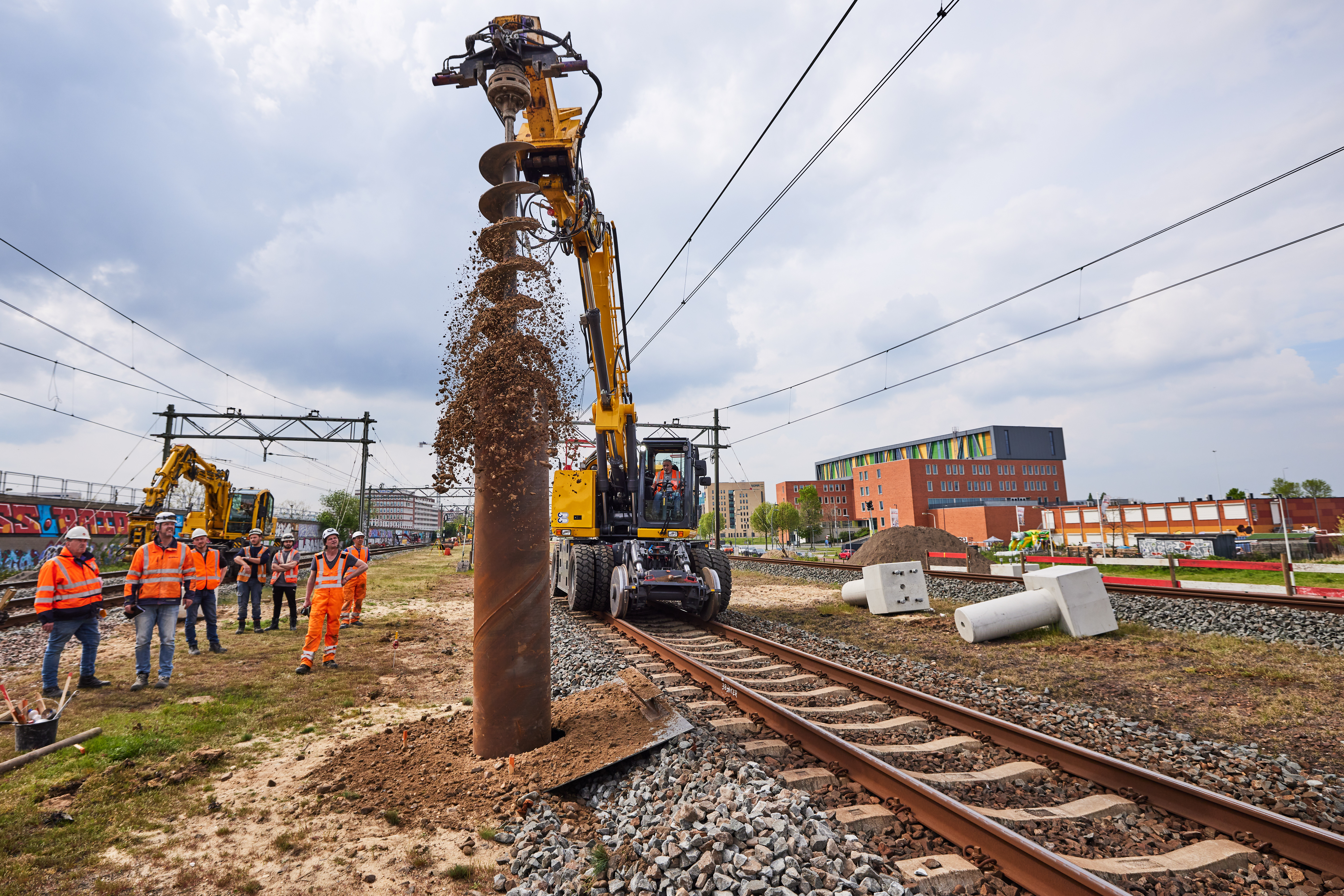 Weer een andere machine graaft gaten voor funderingsblokken voor 82 nieuwe bovenleidingspalen