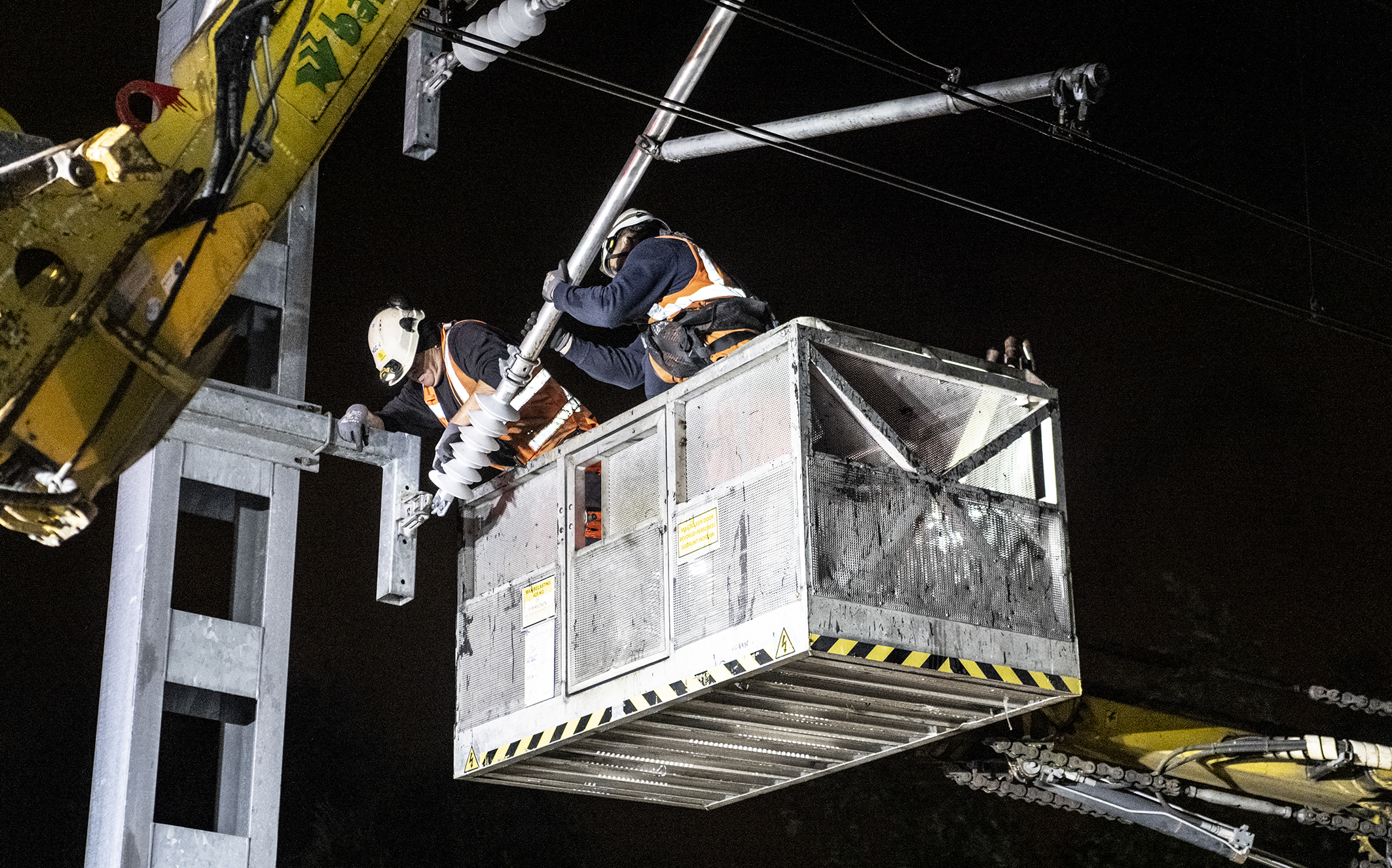 Aan een bovenleidingportaal wordt een isolator geplaatst