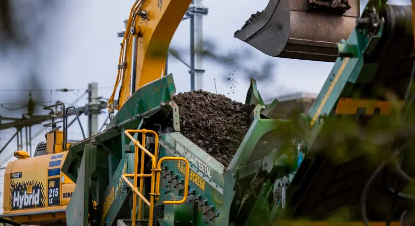 Een shovel werpt de oude ballast in de zeefinstallatie