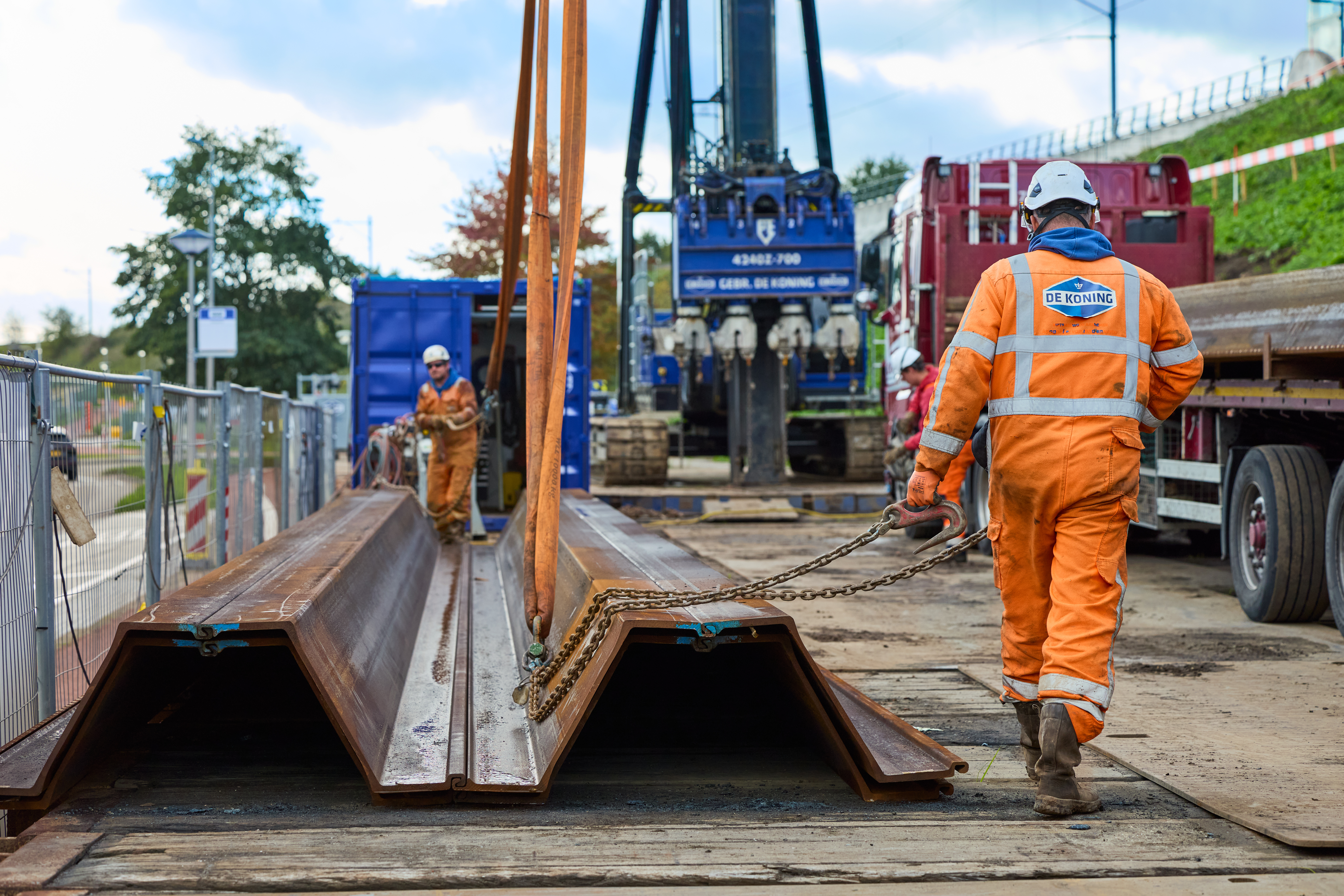 Een trillingsarme damwandmachine drukt deze damwanden van ongeveer 17 meter de grond in
