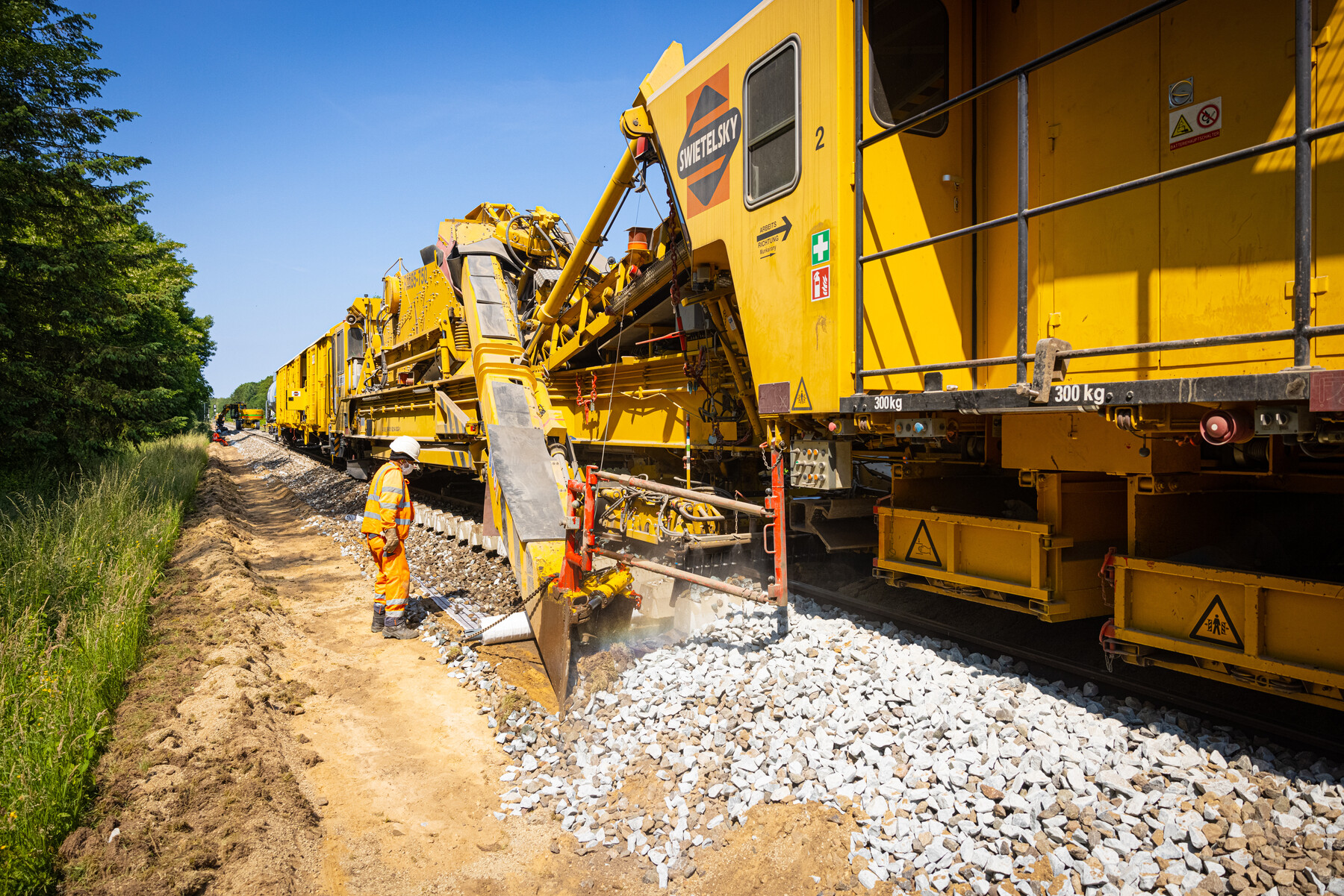De kettinghor tilt het spoor op en harkt met een grote ketting het spoorgrind onder het spoor vandaan en het oud grind wordt afgevoerd en vervangen door nieuwe, deels hergebruikte stenen