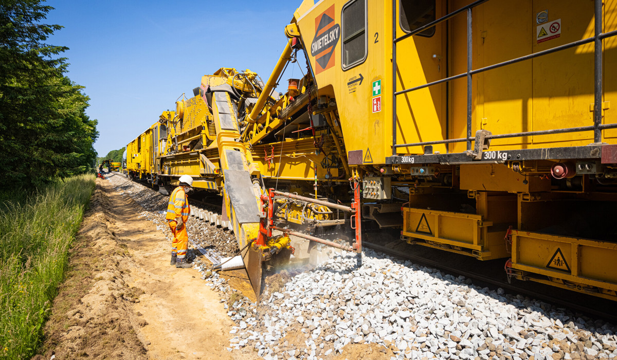 De kettinghor tilt het spoor op en harkt met een grote ketting het spoorgrind onder het spoor vandaan en het oud grind wordt afgevoerd en vervangen door nieuwe, deels hergebruikte stenen