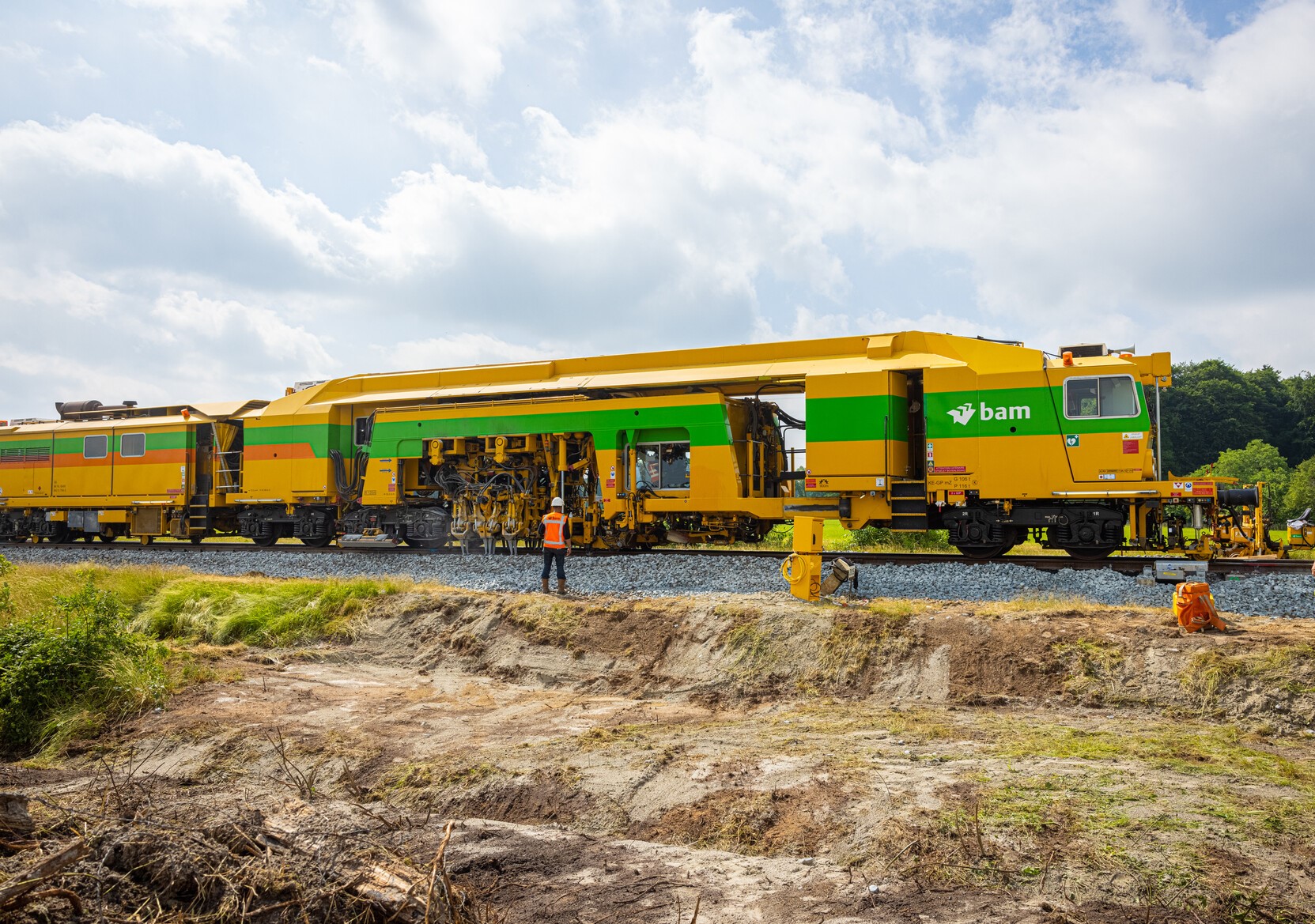 De stopmachine brengt het spoor op de juiste ligging door het spoorgrind op te schudden
