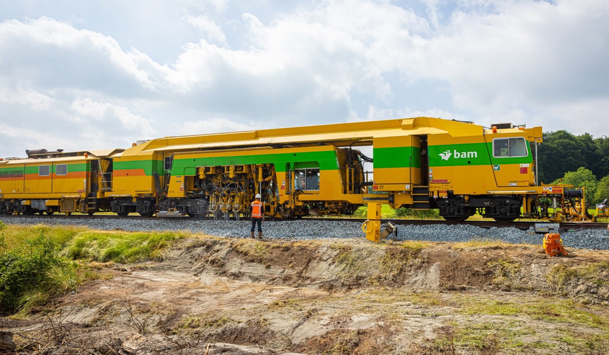 De stopmachine brengt het spoor op de juiste ligging door het spoorgrind op te schudden