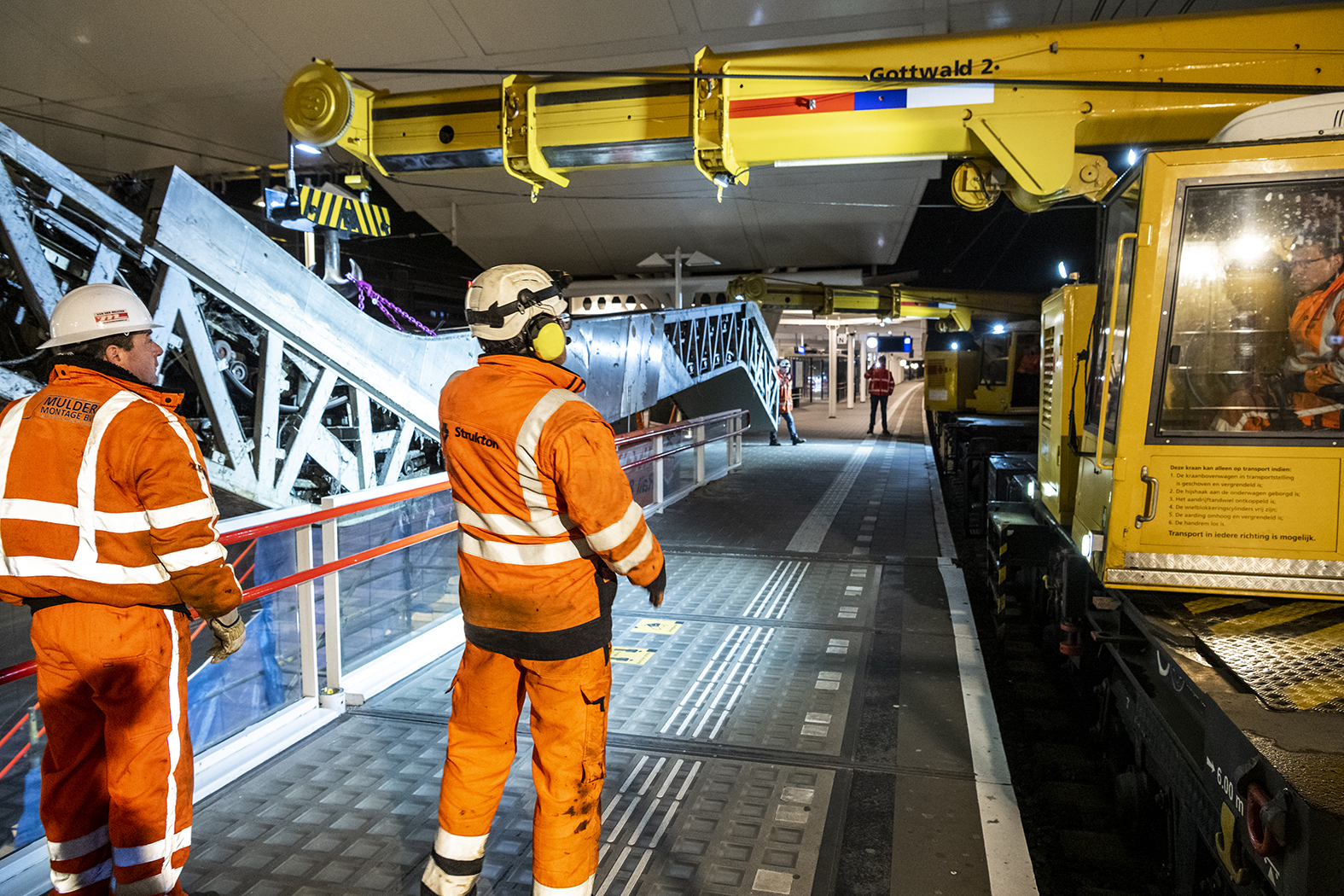 De oude roltrap wordt uitgehesen door twee kranen