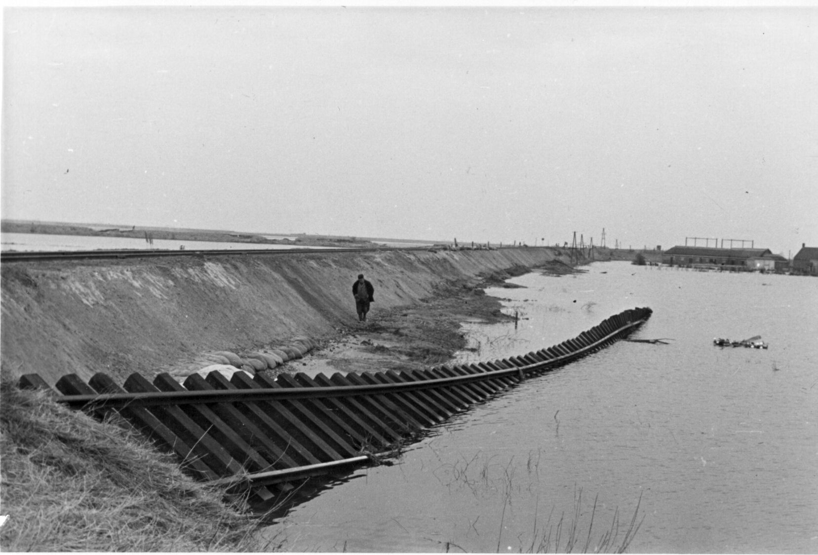Een Zeeuw loopt langs het mistroostige beeld van een spoor onder water.